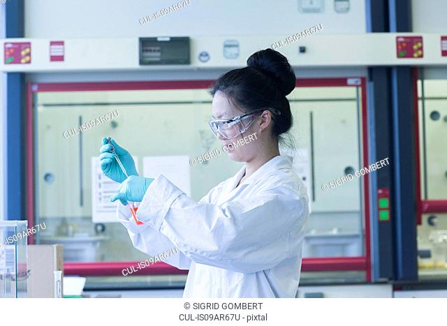 Female scientist in lab pipetting sample into lab beaker