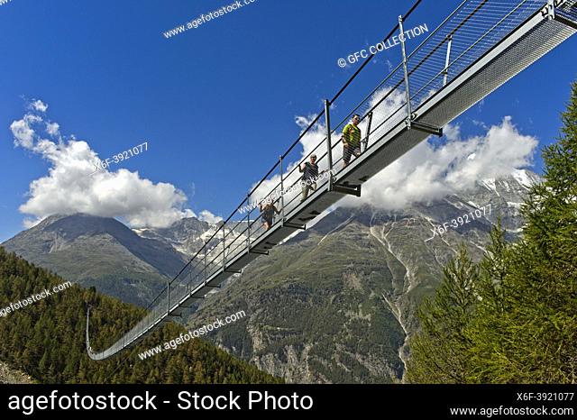 Hikers crossing the Charles Kuonen Suspension Bridge, the longest pedestrian suspension bridge in the Alps, Randa, Valais, Switzerland