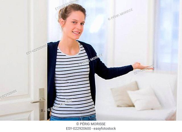 Young attractive woman welcoming you in his house