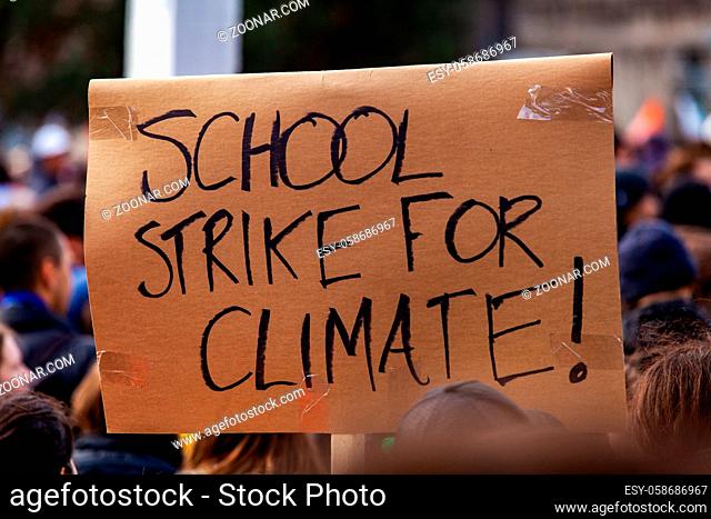 A cardboard sign, reading school strike for climate, is seen closeup as ecological activists unite against global warming during a peaceful street demonstration