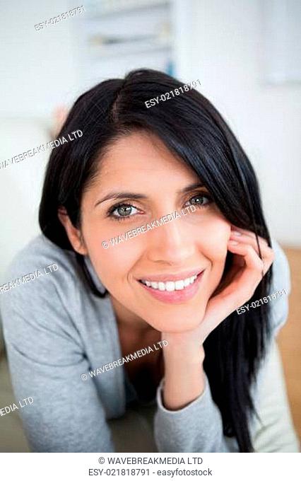 Smiling woman holding her head with her hand in a living room