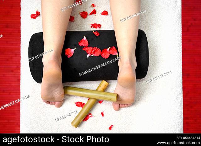 Female feet, bamboo sticks and flower petals. Thai massage, Spa and skin care concept