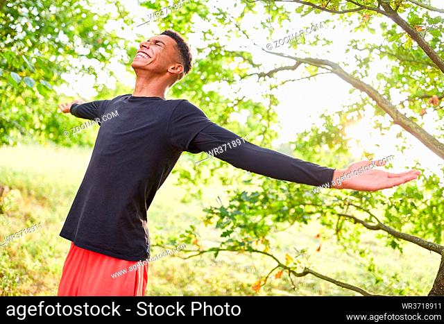 Glücklicher junger Mann beim Atmen in der frischen Luft in der Natur im Sommer