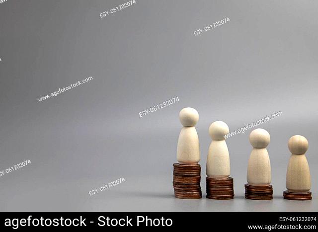 Miniature people standing on piles of different heights of coins. The concepts of person and wealth. investment and teamwork growth copy space