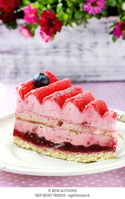 Pink layer cake decorated with fresh fruits on wooden table. Selective focus