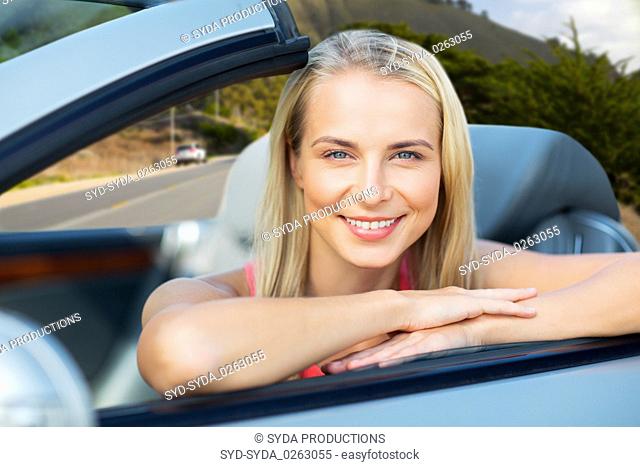 happy woman in convertible car over big sur hills