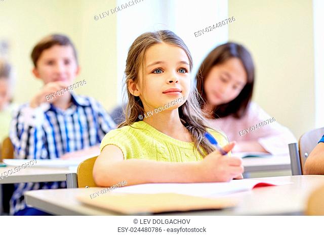 education, elementary school, learning, children and people concept - student girl with group of classmates on lesson in classroom