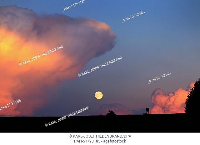 A view of the full moon next to clouds illuminated by the setting sun at the Auerberg near Bernbeuren, Germany, 08 September 2014