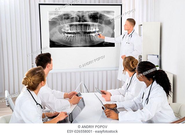 Young Male Doctor Explaining Human Teeth X-ray To His Colleagues