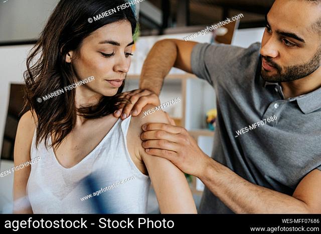 Physiotherapist working on shoulder of female patient in practice