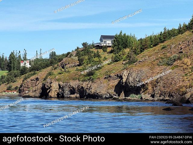 20 August 2023, Iceland, Akureyri: A house stands above a rock on the shore of Eyjafjördur fjord. Photo: Soeren Stache/dpa