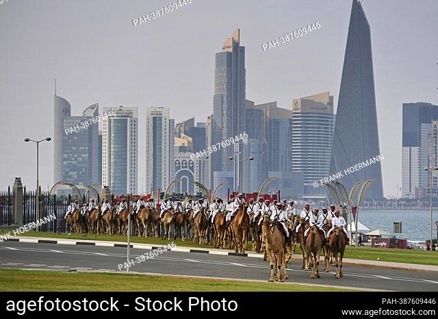 Impressions from Doha / Qatar on December 7th, 2022. Mounted camel guards on camels ride in front of the Doha skyline to the Amiri Divan seat of government of...