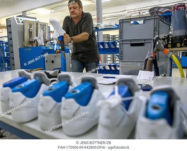 An employee works on shoes mid-way through the production process in the workshop of the German vegan sports shoe manufacturer Lunge in Duessin, Germany