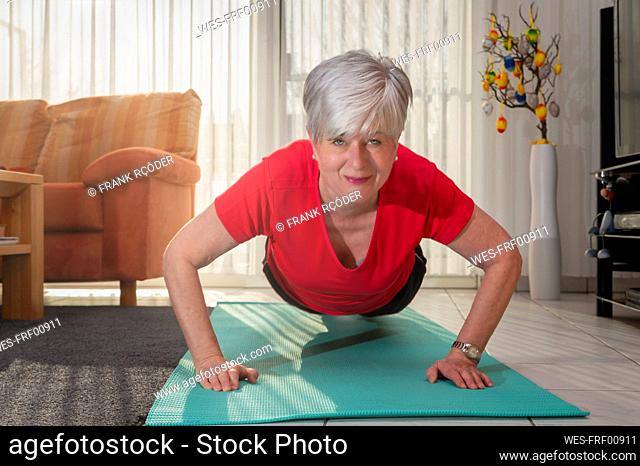Happy senior woman doing pushup at home