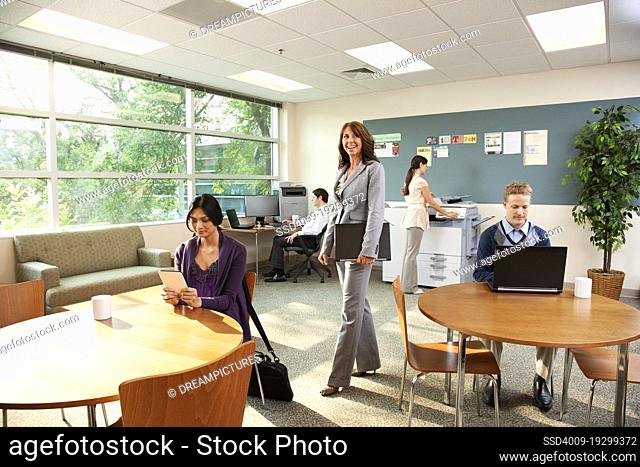 Portrait of a confident business woman standing in office with her piers working around her