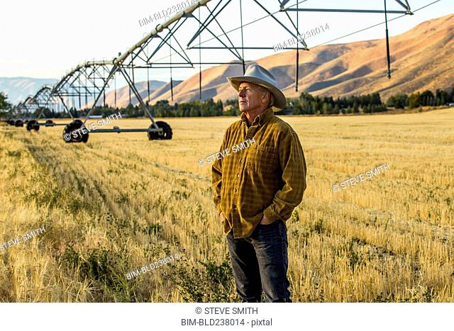 Caucasian farmer standing near irrigation equipment