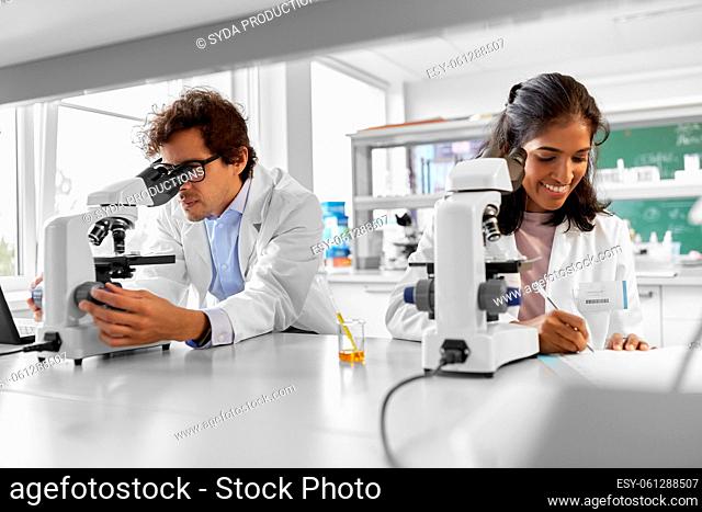 scientists with microscopes working in laboratory