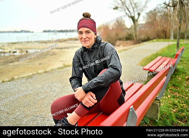 PRODUCTION - 16 December 2021, Baden-Wuerttemberg, Lindau Am Bodenseee: The athlete Valeria Kleiner is sitting on a park bench on the shore of Lake Constance