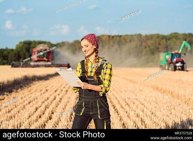 armer with clipboard on the wheat field doing bookkeeping on the ongoing harvest