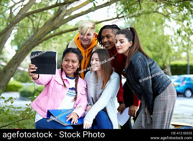 Happy college students taking selfie with digital tablet in park