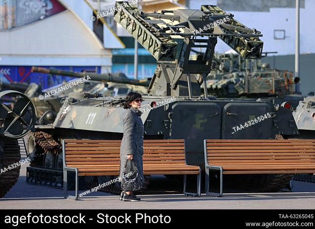 RUSSIA, LUGANSK - OCTOBER 11, 2023: A woman stands near an anti-aircraft missile system on display as an exhibition of military equipment captured from Ukraine...