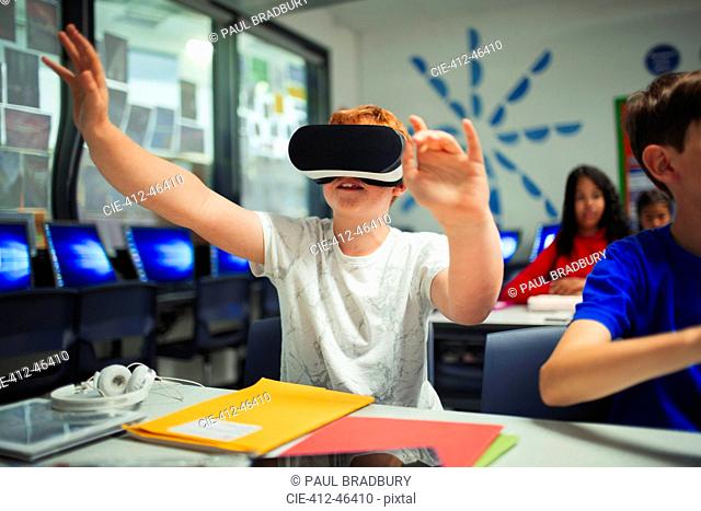 Curious junior high school boy student using virtual reality simulator in classroom