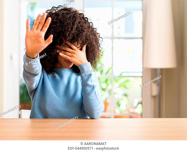 African american woman at home covering eyes with hands and doing stop gesture with sad and fear expression. Embarrassed and negative concept