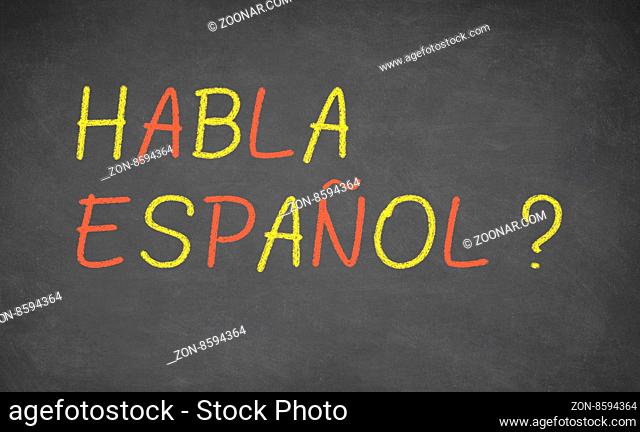 Spanish language learning concept image. Teacher or student wrote HABLA ESPANOL on blackboard during spanish language course class