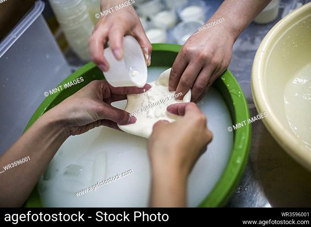 High angle close up of cheese-making, cream and curds are poured into burrata purses