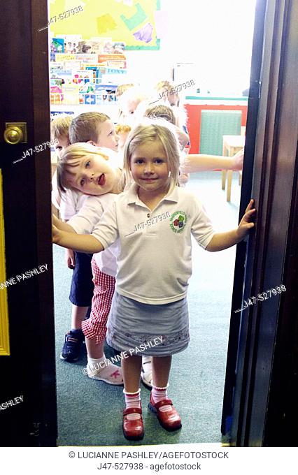 Group of 2-4 year old children standing in the doorway of the classroom at nursery