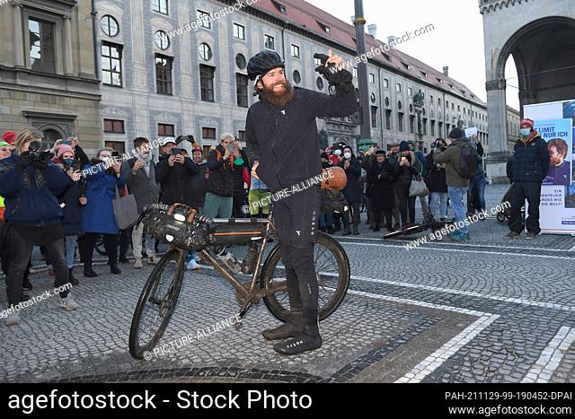 29 November 2021, Bavaria, Munich: German extreme athlete Jonas Deichmann stands at Odeonsplatz at the finish line of his triathlon around the world and laughs