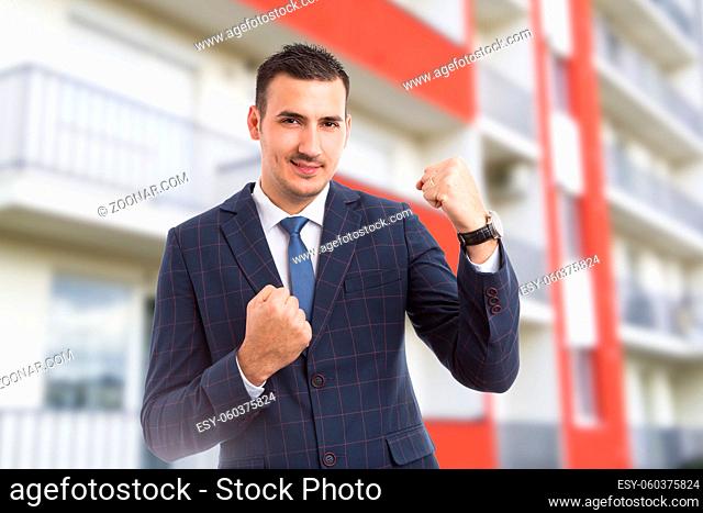 Cheerful joyful realtor or sales man acting happy on new apartment building background