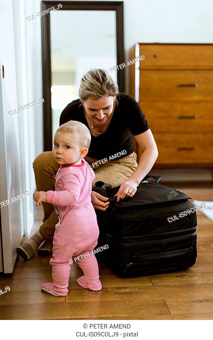 Mother on luggage with baby in bedroom