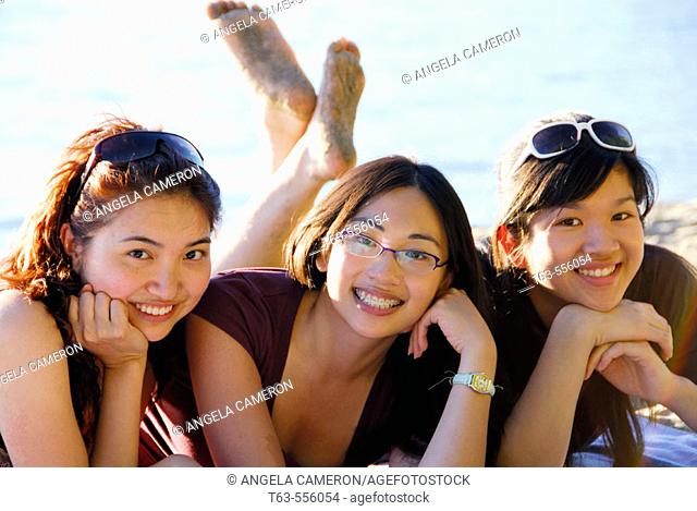 3 asian women laying together on beach