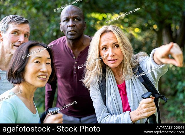 Senior woman giving directions to diverse group of people while pointing