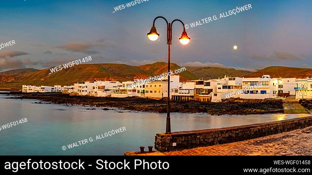 Spain, Canary Islands, Arrieta, Panoramic view of village on shore of Lanzarote island at dusk