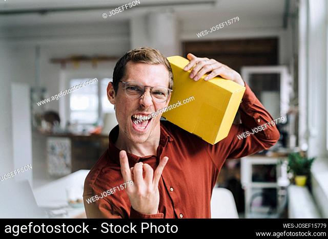 Cheerful businessman gesturing and standing with box in office