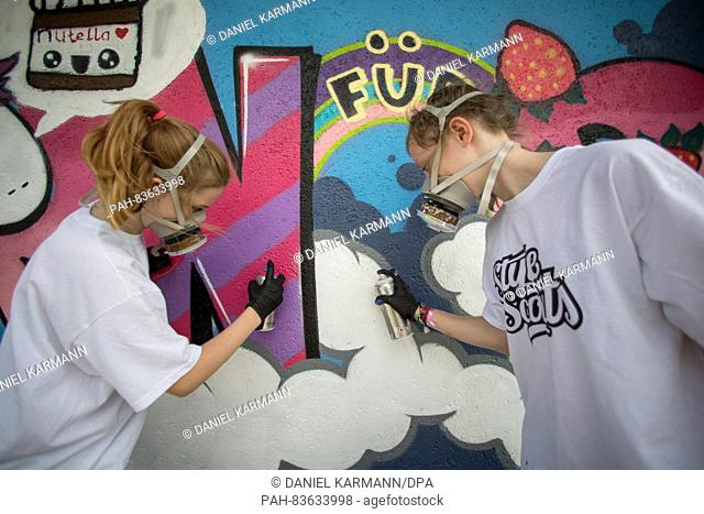 Jessica (L) and Denise, participants in a graffiti workshop, work on graffiti on a wall in Rosstal,  Germany, 30 August 2016