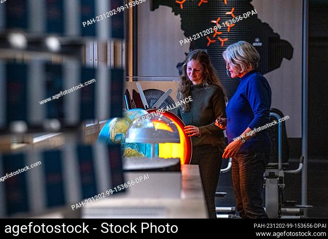 PRODUCTION - 30 November 2023, Bavaria, Straubing: Two museum employees stand at a globe in an exhibition room of the Nawareum