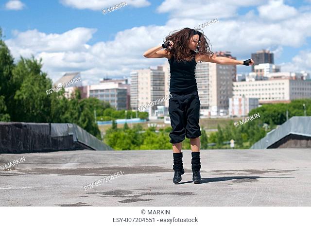 Beautiful teenage girl dancing hip-hop over urban city landscape