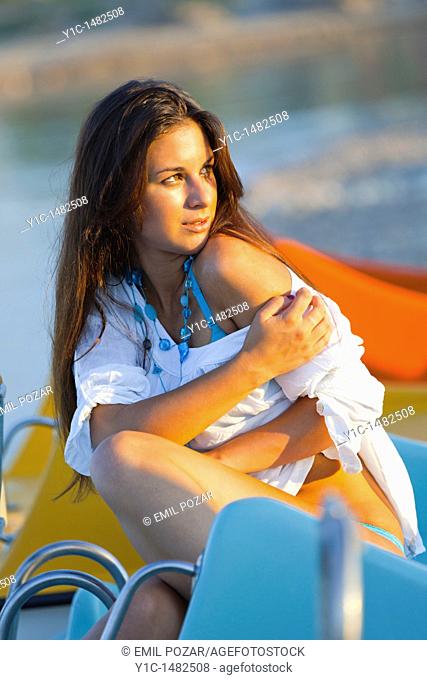 Attractive young woman on the beach is enjoying a warm sunset light