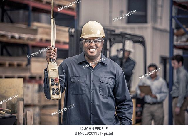 African American worker holding control panel in factory