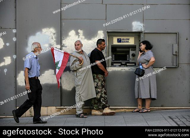 26 September 2022, Lebanon, Beirut: Lebanese depositors stands next to a broken ATM machine outside a fortified local bank in Beirut