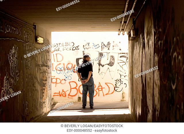 Man in a train underpass with grafitti on the walls in Maremma, Italy