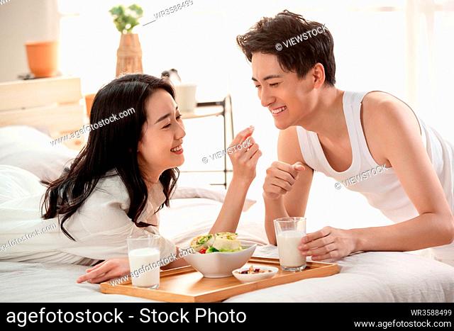 Happy young couple to have breakfast in bed