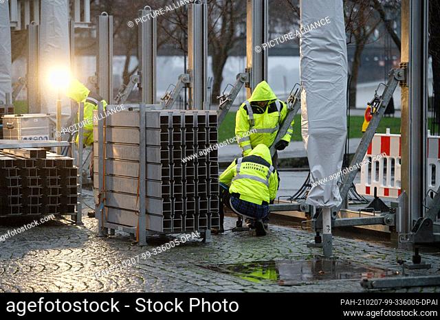 07 February 2021, North Rhine-Westphalia, Cologne: Workers build a flood protection wall on the banks of the Rhine in front of the old town