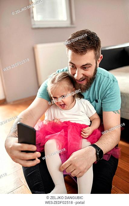 Father and daughter taking a selfie, girl wearing pink tutu