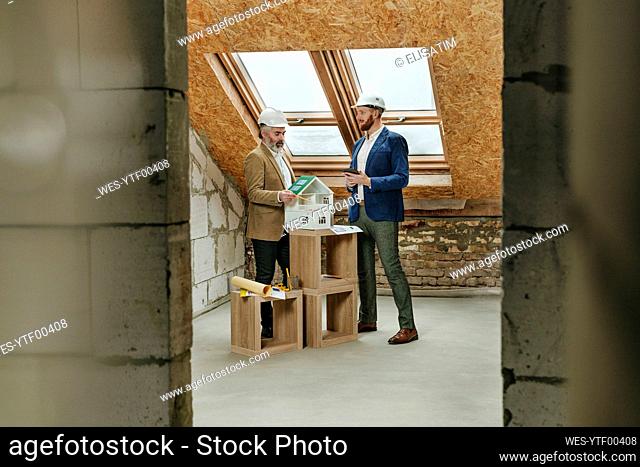Architects discussing over house model at construction site