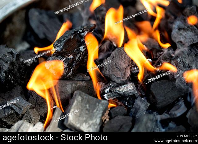 Angzündete Holzkohle mit Flammen auf dem Grill