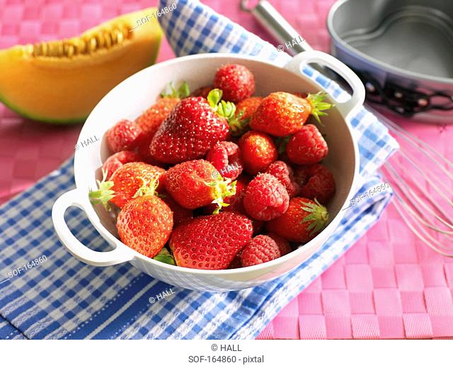 Raspberries and strawberries in a colander